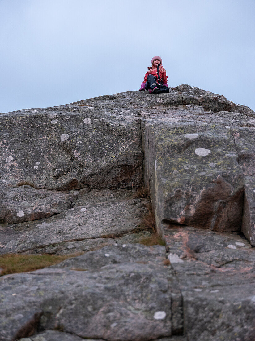 Child sitting on top of rock