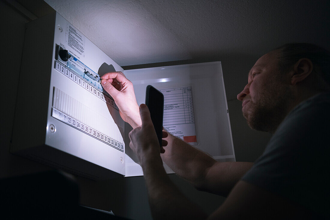 Electrician checking electrical cabinet at night