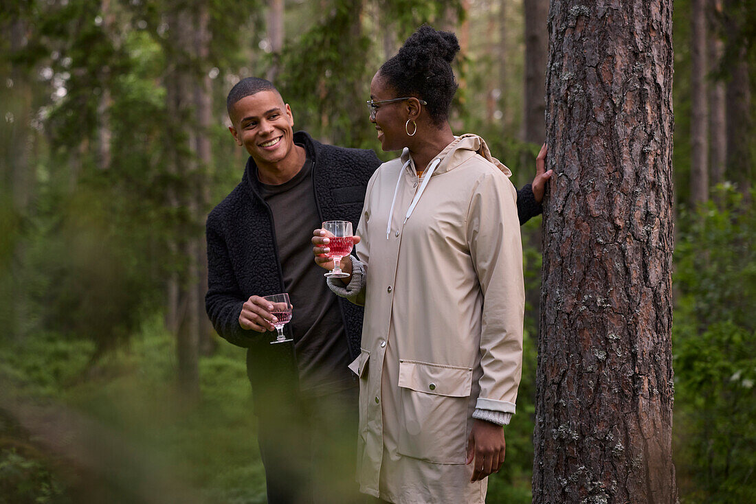 Smiling couple holding wineglasses in forest