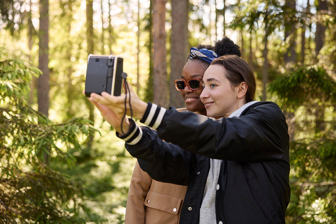 Smiling women taking selfie in forest