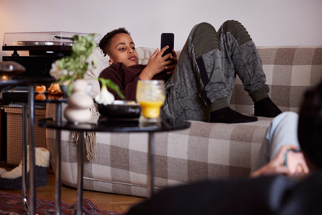 Boy lying on sofa and using phone