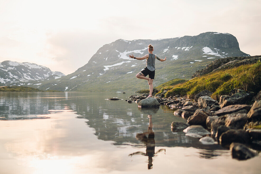 Woman doing yoga at lake in mountains