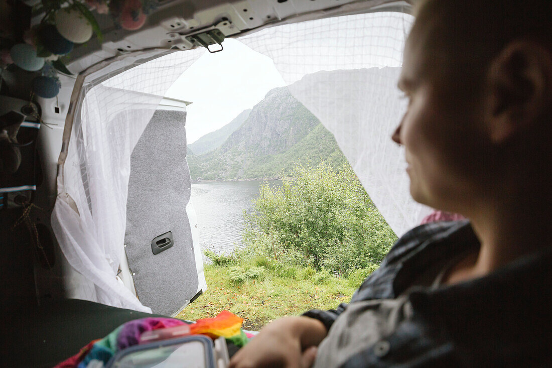 Woman in camper van looking at lake