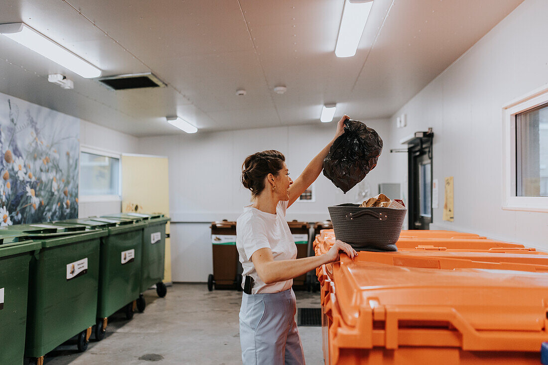 Smiling woman putting recycling into bins