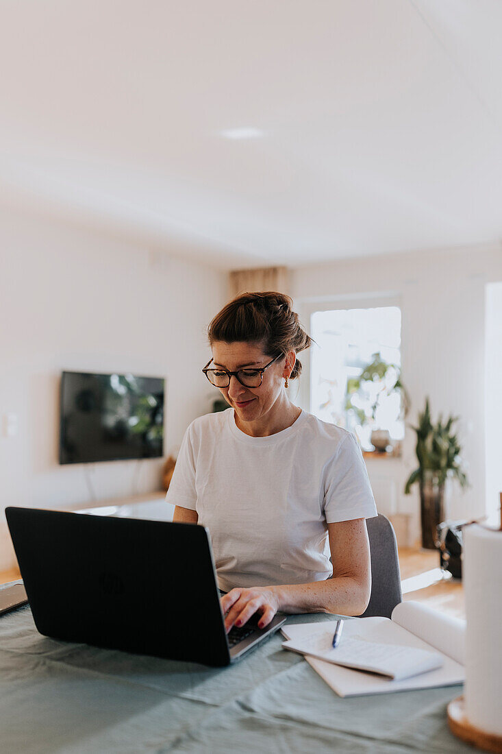 Smiling woman using laptop at home