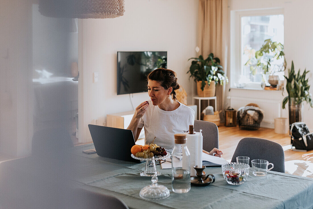 Lächelnde Frau, die zu Hause einen Laptop benutzt