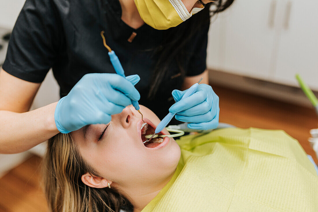 Zahnärztin prüft Zähne eines Patienten