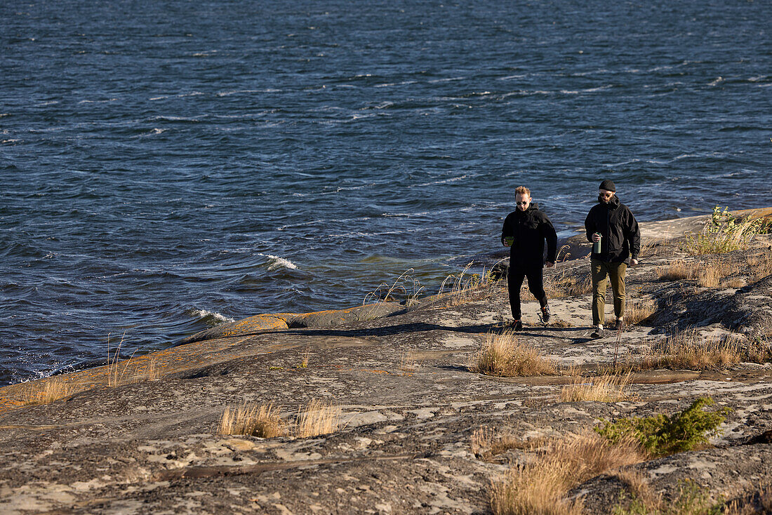 View of men walking at rocky coast