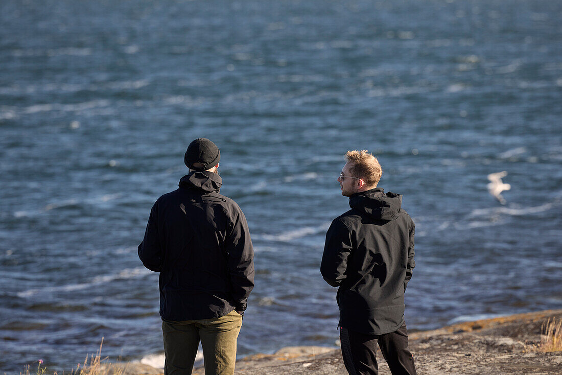 Rear view of men standing at sea