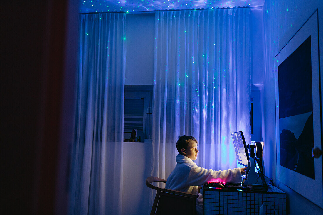 Boy at desk using computer at night