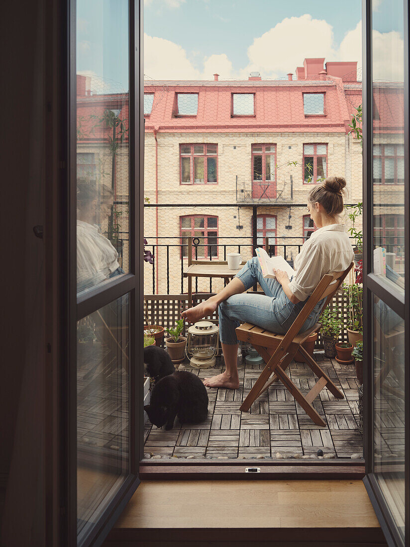 Frau liest ein Buch auf dem Balkon