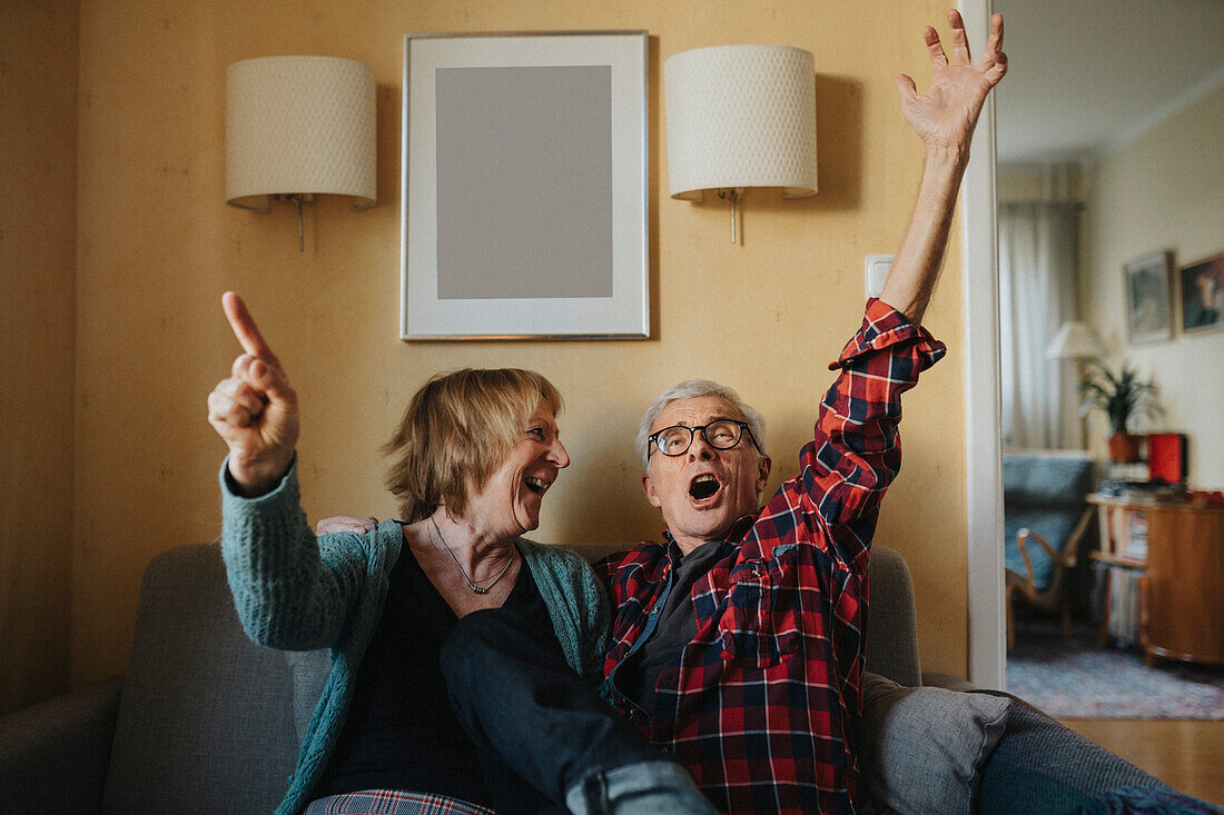 Älteres Paar auf dem Sofa sitzend und singend