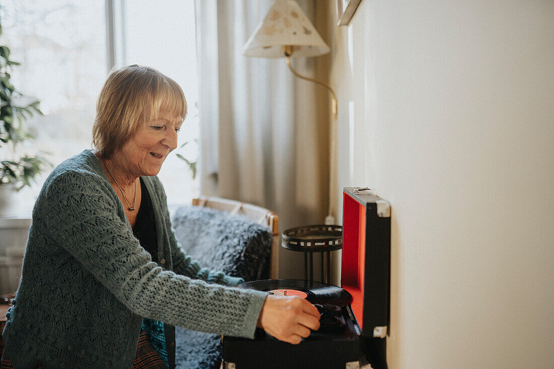 Senior woman using gramophone at home