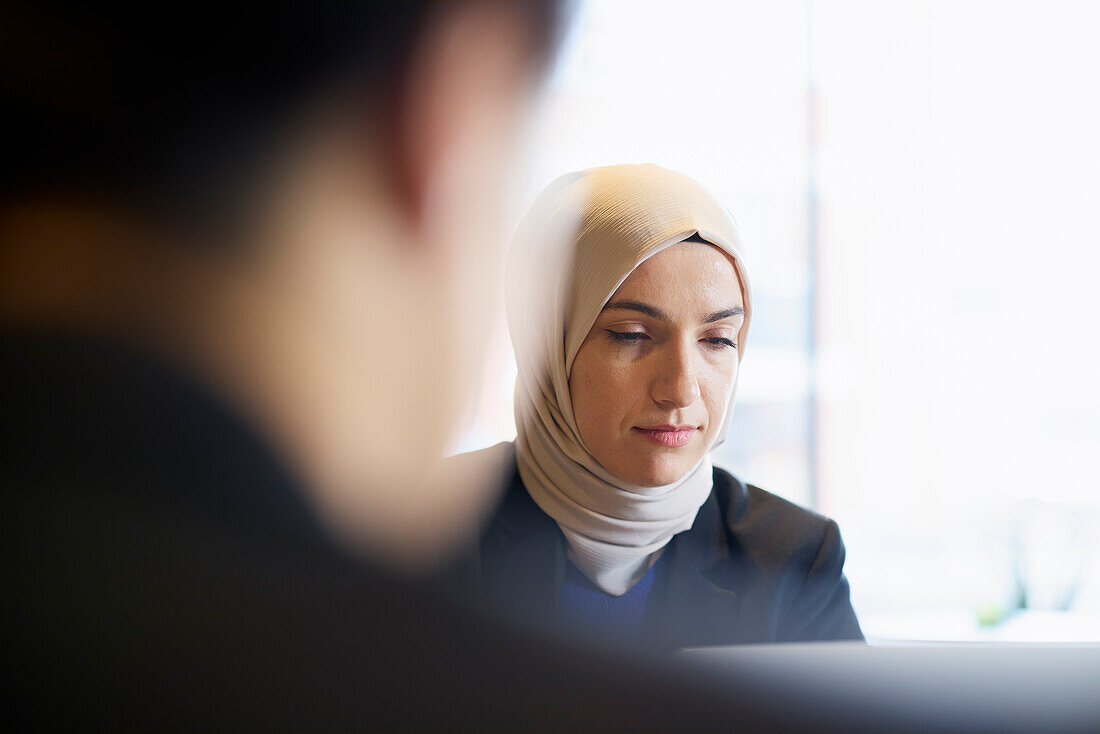 Frau mit Kopftuch im Café sitzend