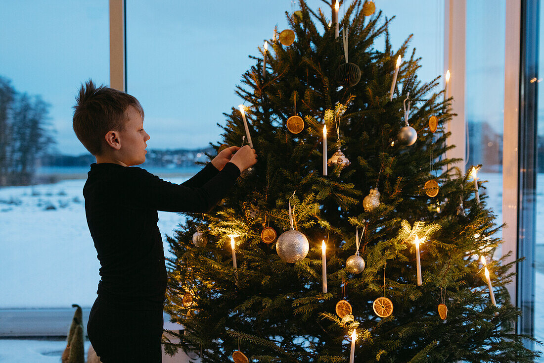 Junge schmückt Weihnachtsbaum zu Hause