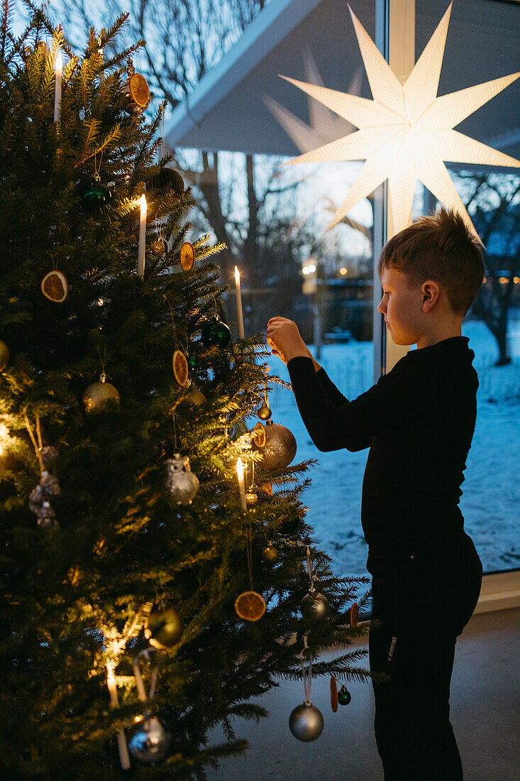 Junge beim Schmücken des Weihnachtsbaums zu Hause