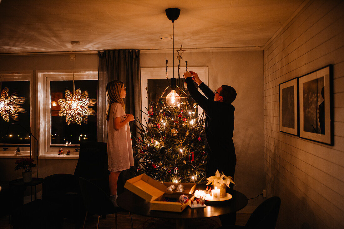 Vater und Tochter beim Schmücken des Weihnachtsbaums