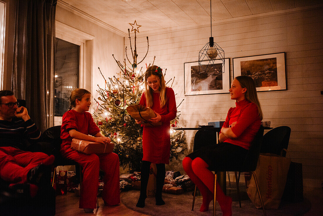 Vater und Töchter beim Öffnen von Weihnachtsgeschenken