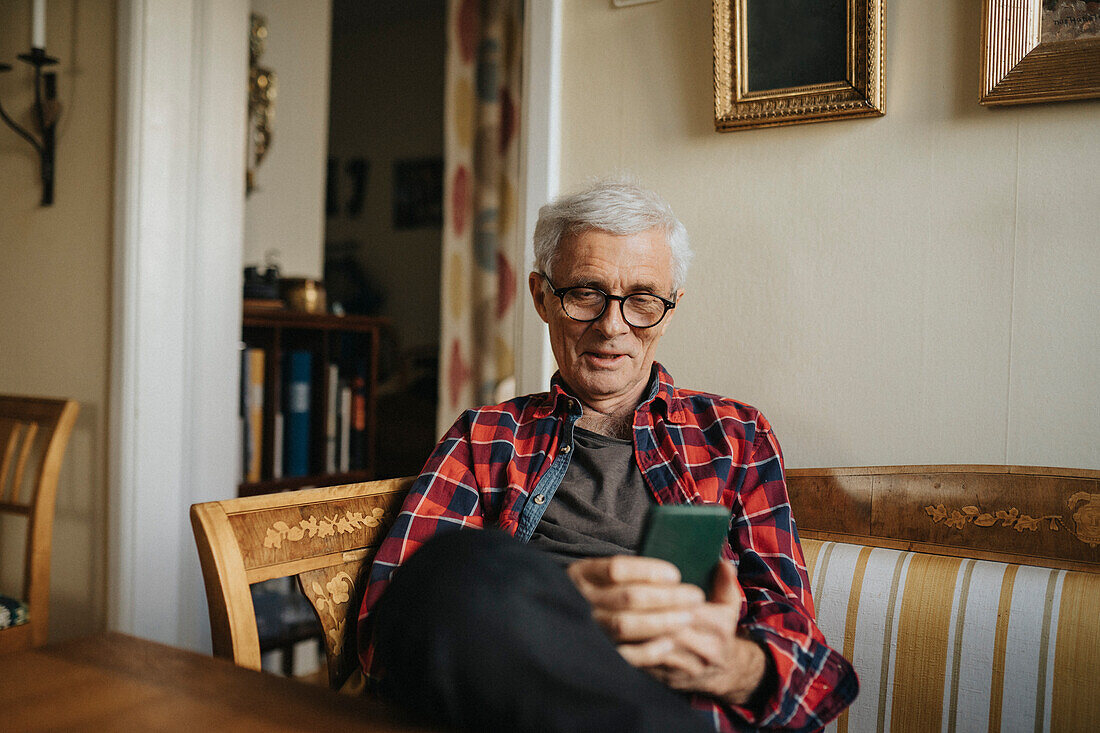 Älterer Mann benutzt Smartphone zu Hause
