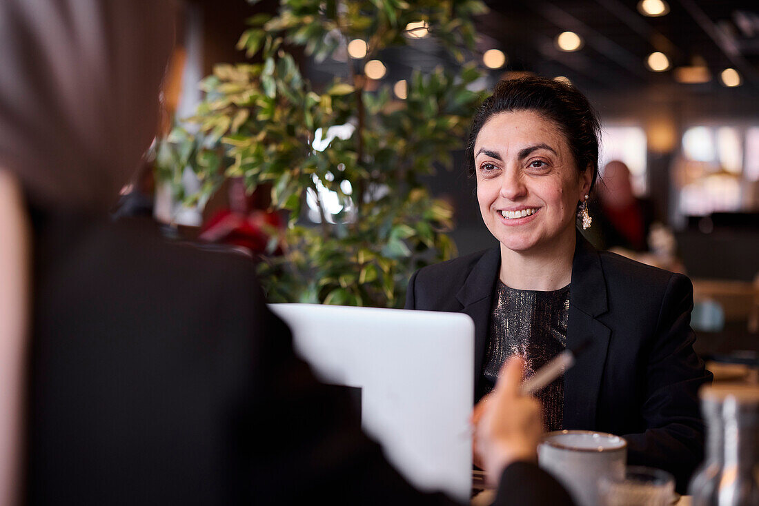 Smiling businesswoman using laptop in cafe