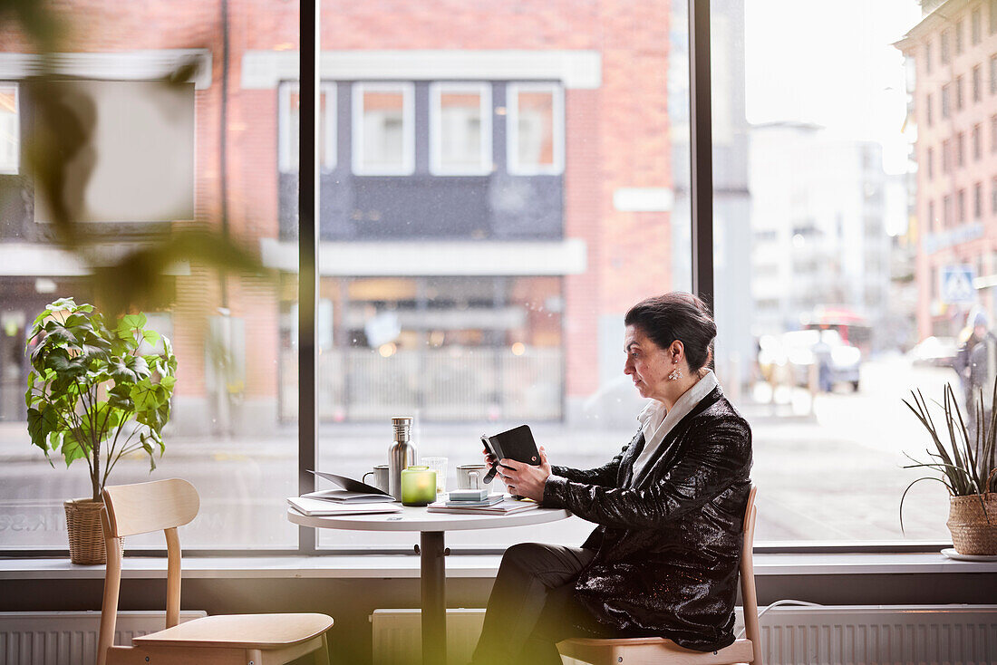 Reife Frau mit Mobiltelefon im Café