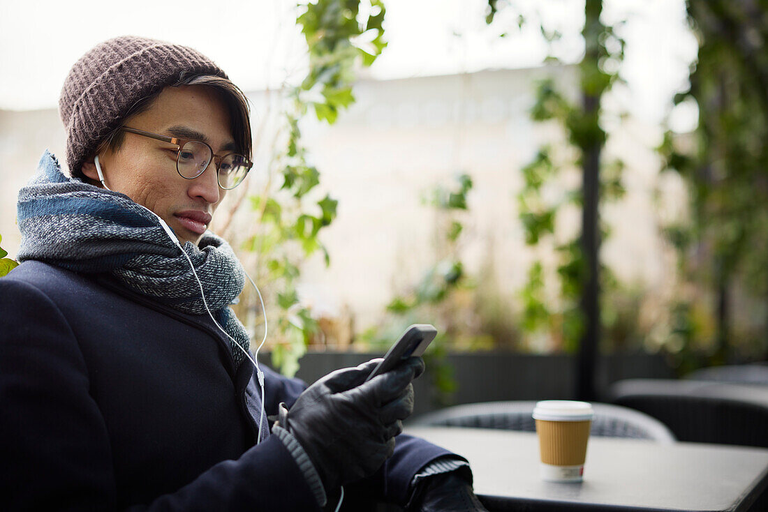 Man using cell phone in outdoor cafe