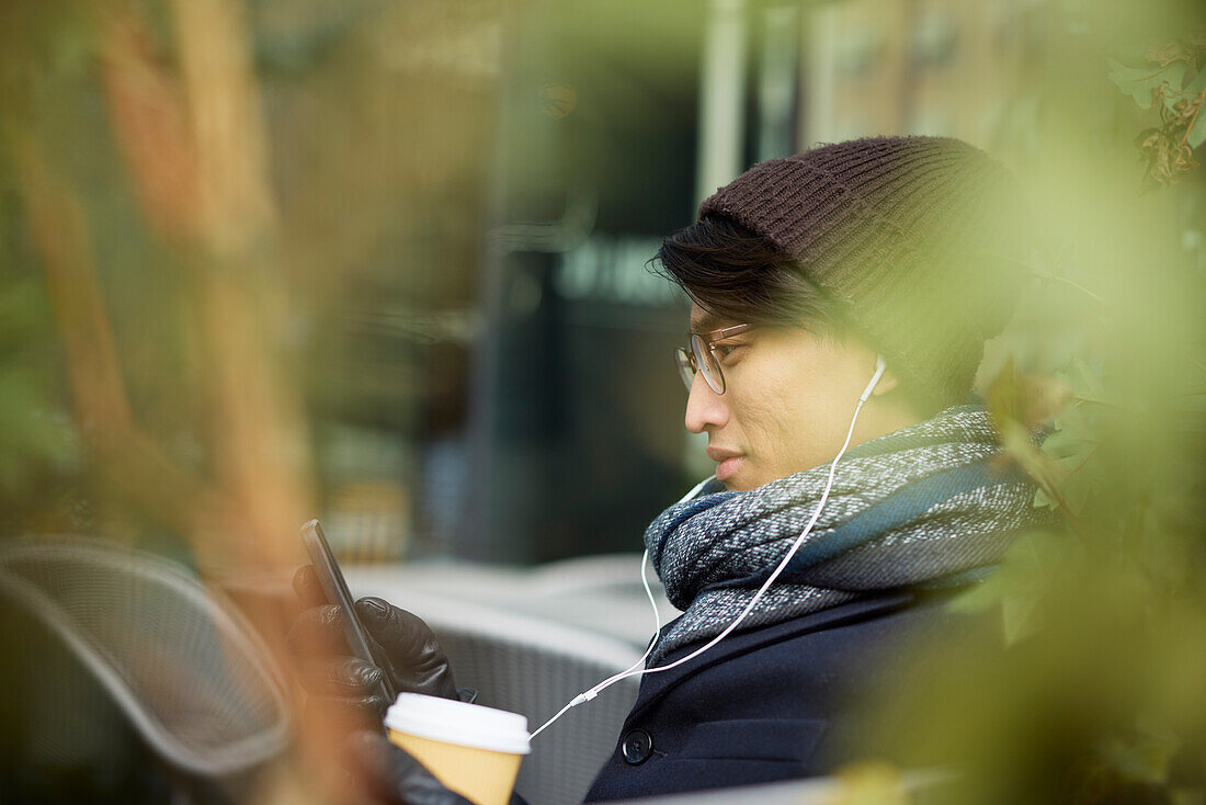 Man using cell phone in outdoor cafe