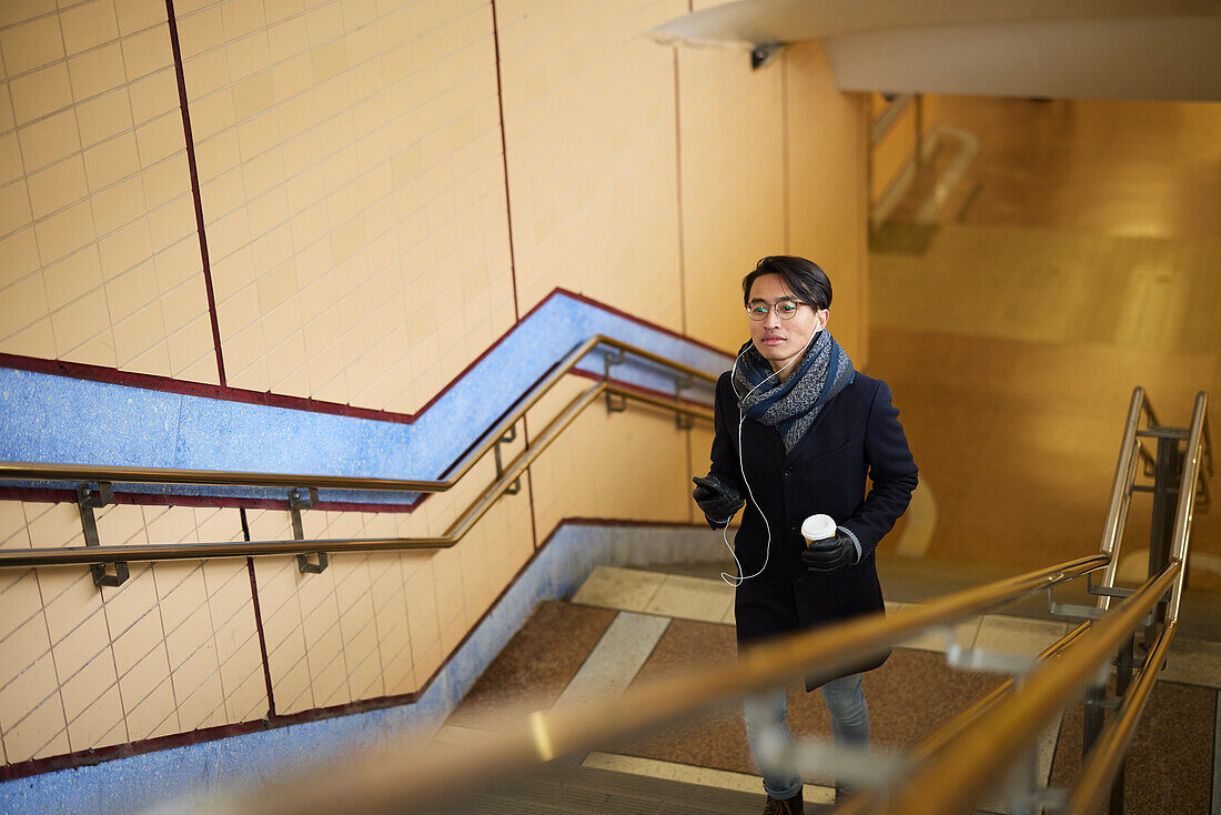 Man with coffee cup walking upstairs