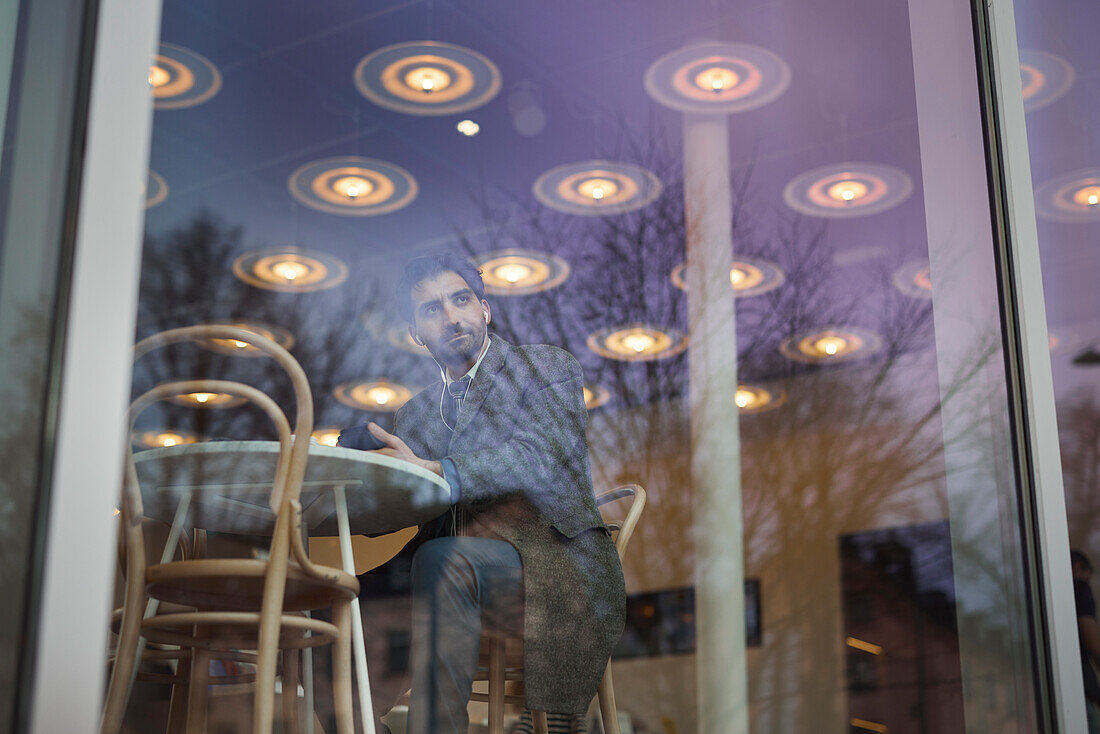 Eleganter Mann mit Smartphone im Cafe sitzend