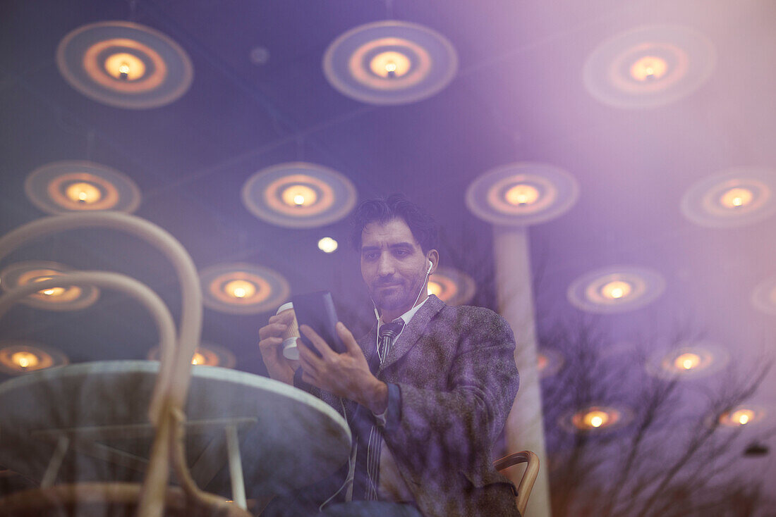 Elegant man with smartphone sitting in cafe