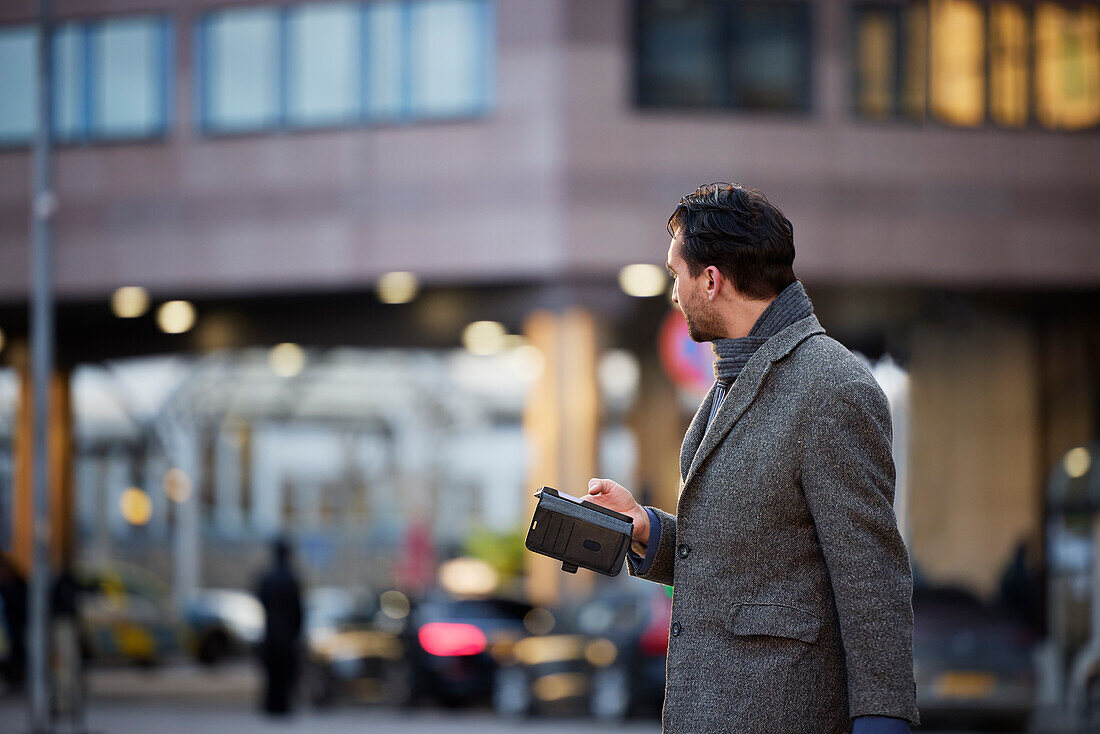Businessman using phone outdoors in city