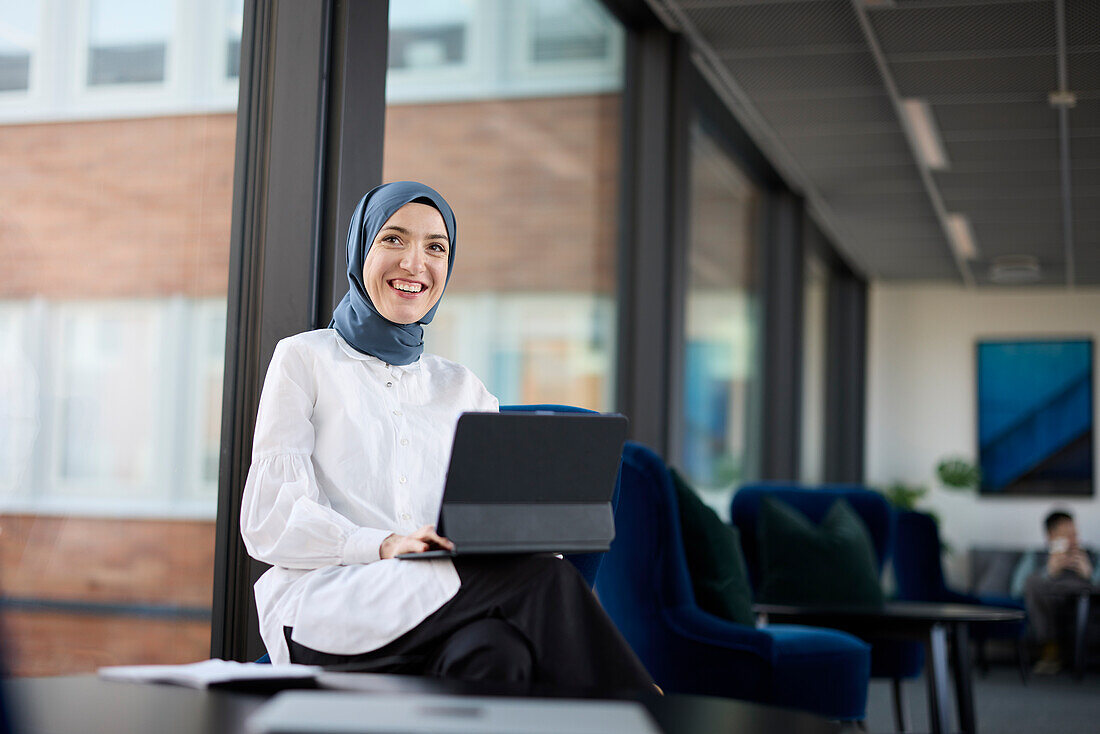 Geschäftsfrau im Hijab mit digitalem Tablet im Büro