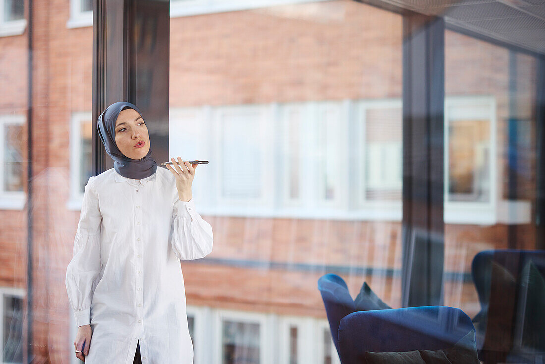 Businesswoman in hijab using phone in office