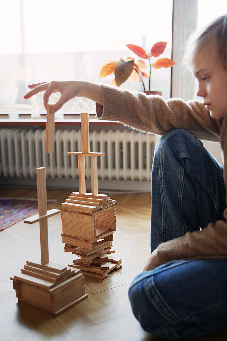 Girl arranging tower of wooden blocks