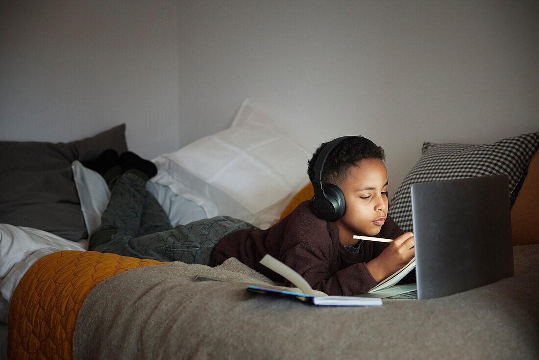 Boy doing homework with laptop in his bedroom