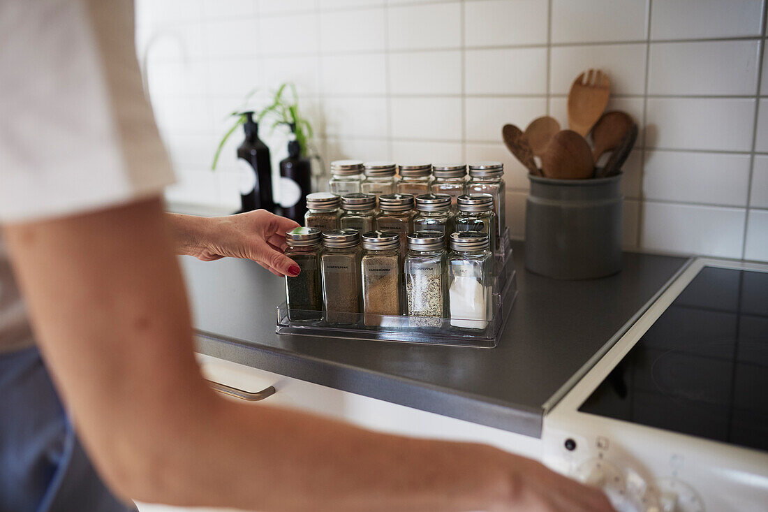 Woman's hands checking spices on spice rack