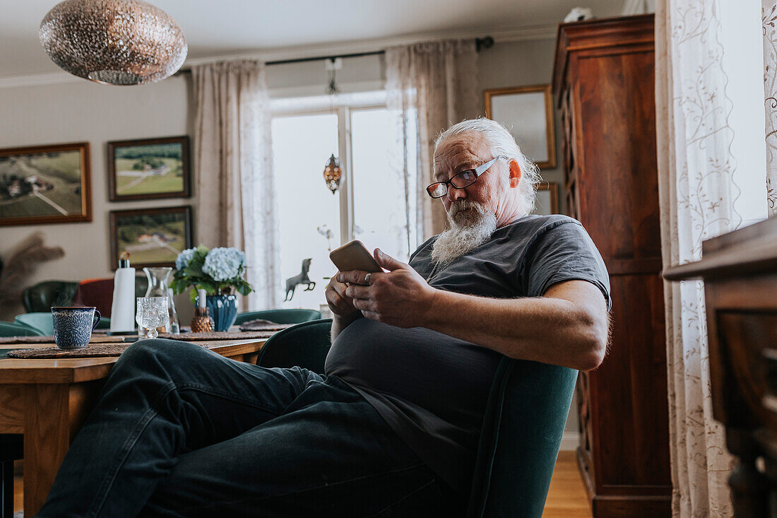 Mann sitzt und benutzt ein Mobiltelefon