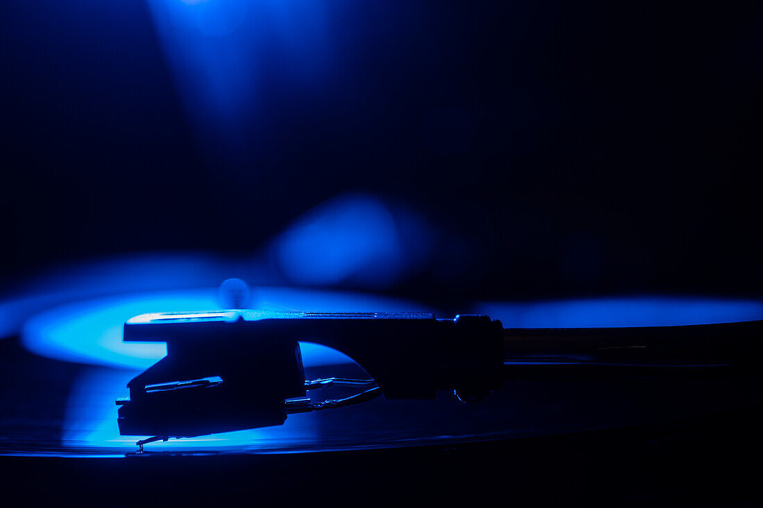 Close-up of a record player needle on record in blue light