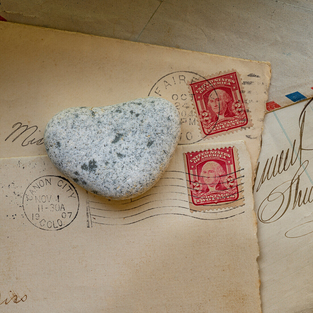 Alte Briefumschläge mit Briefmarken und herzförmigen Steinen