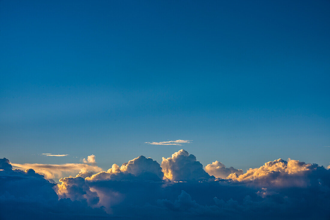 Kumuluswolken am blauen Himmel bei Sonnenaufgang