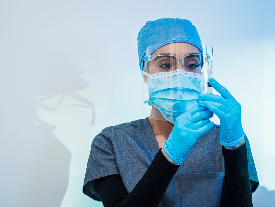 Krankenschwester mit Gesichtsmaske und Schutzschild bei der Vorbereitung der Covid-19-Impfung