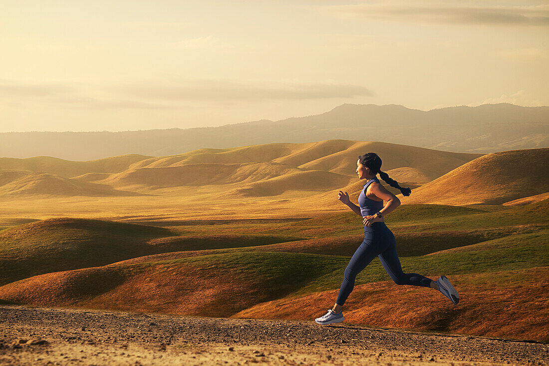Frau beim Joggen in der Landschaft bei Sonnenuntergang