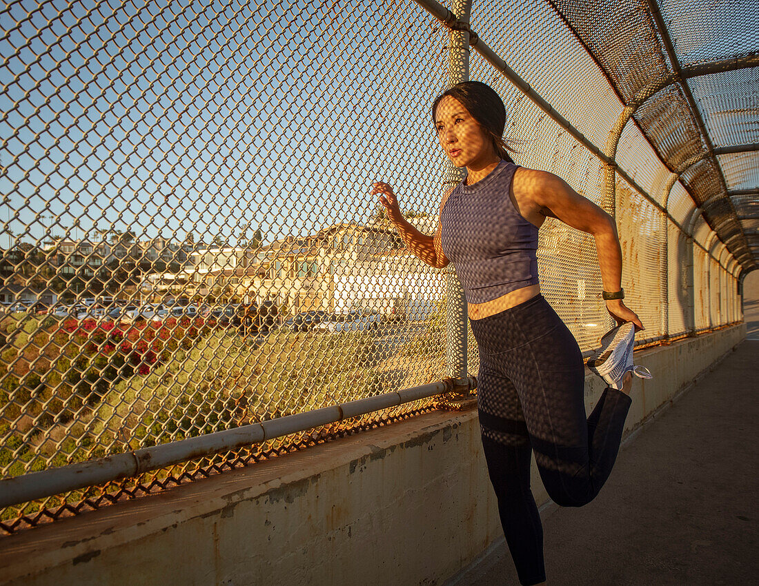 Athlete woman stretching at fence