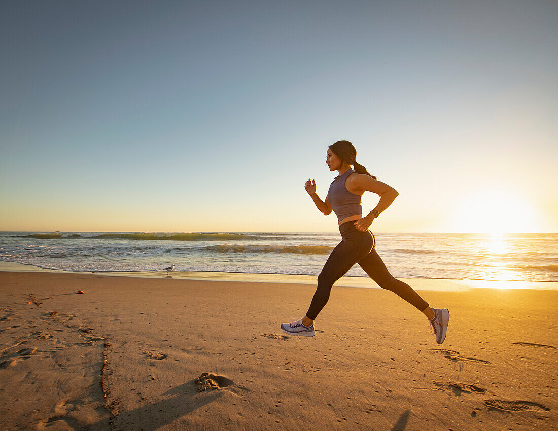 Woman jogging on beach at sunset