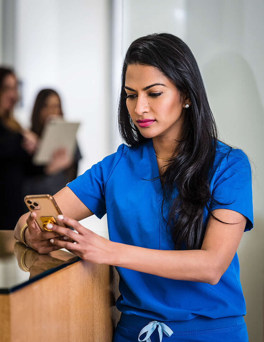 Female doctor with smart phone at reception desk