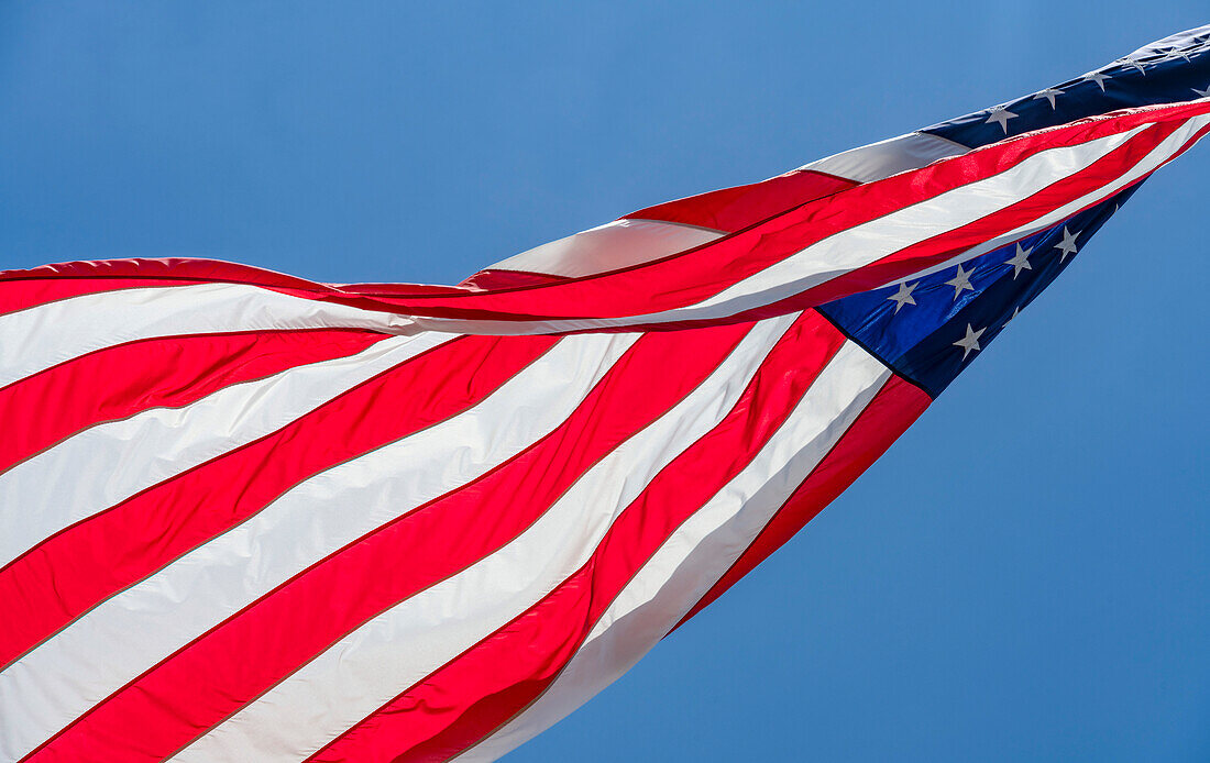 Low angle view of American flag waving in wind against clear sky