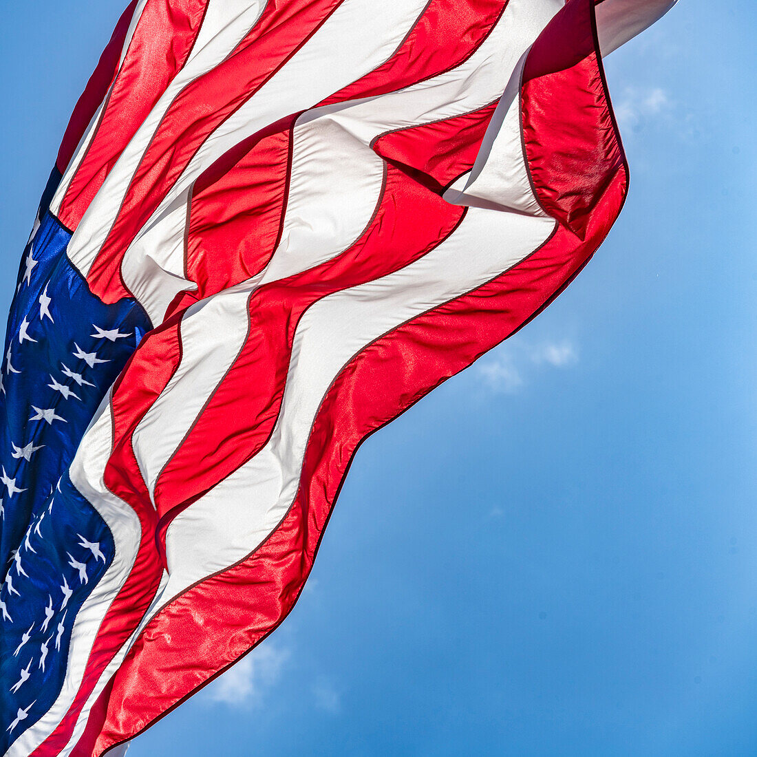 Low angle view of American flag waving in wind against clear sky