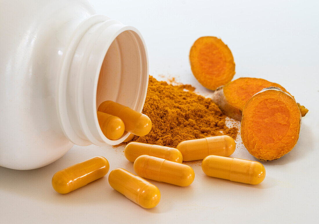 Turmeric powder, root and capsules on white background