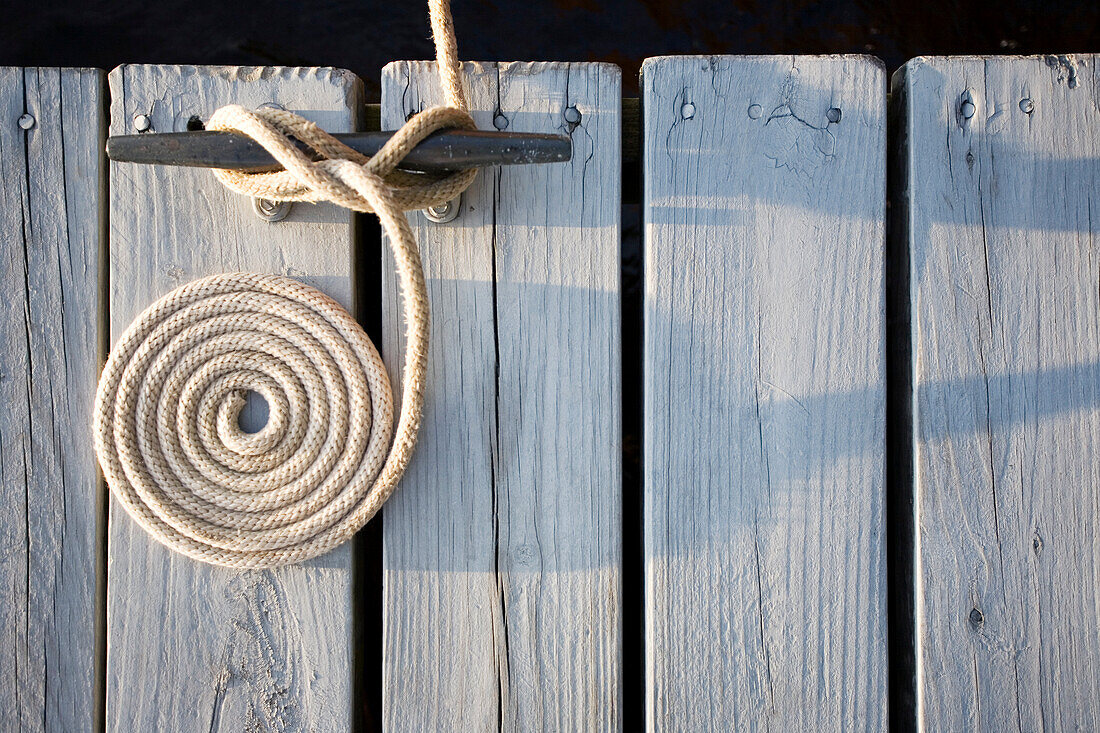 Overhead view of coiled rope tied around bollard