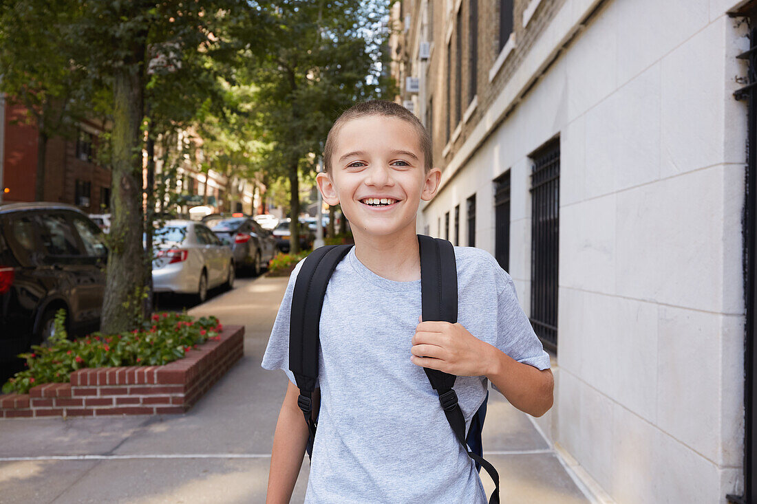 USA, New York, New York City, Porträt eines lächelnden Jungen (8-9) mit Rucksack in der Stadt